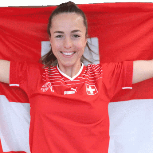A Woman Wearing A Red Puma Jersey Holds A Swiss Flag GIF