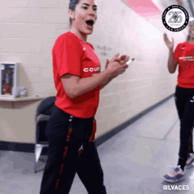 A Woman Wearing A Red Shirt That Says Court Is Standing In A Hallway GIF