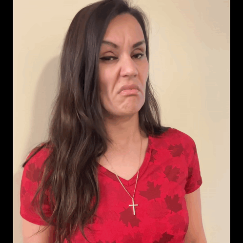 A Woman Wearing A Red Shirt With Maple Leaves On It Makes A Face GIF