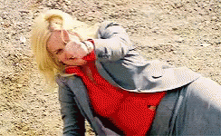 A Woman Wearing A Red Sweater And A Grey Jacket Is Laying On The Ground GIF