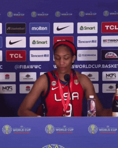 A Woman Wearing A Red Usa Jersey Stands In Front Of A Blue Wall GIF