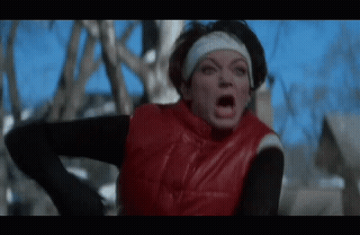 A Woman Wearing A Red Vest And A Headband Is Making A Funny Face . GIF
