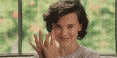 A Woman Wearing A Ring On Her Finger Is Smiling And Looking At The Camera GIF