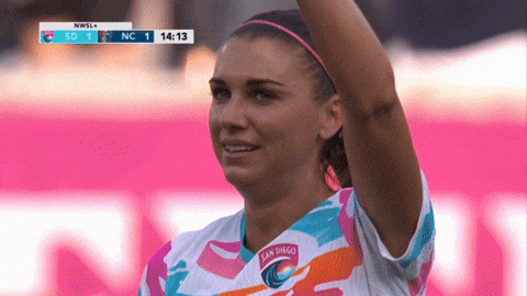 A Woman Wearing A San Diego Soccer Jersey Stands In Front Of A Scoreboard GIF