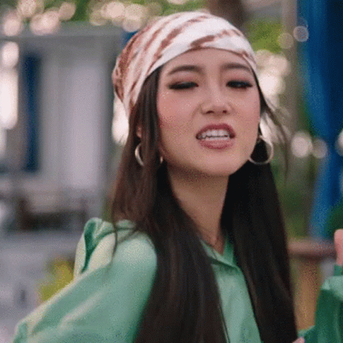 A Woman Wearing A Scarf And Earrings Is Making A Funny Face . GIF
