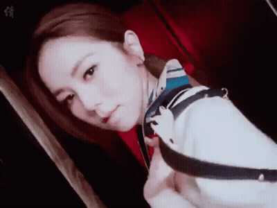 A Woman Wearing A Scarf Around Her Neck Is Taking A Selfie In A Dark Room . GIF