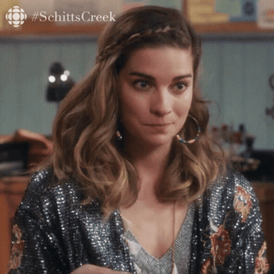 A Woman Wearing A Sequined Jacket And Hoop Earrings With #Schittscreek Written On The Bottom GIF