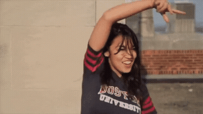 A Woman Wearing A Shirt That Says Boston University Is Smiling GIF