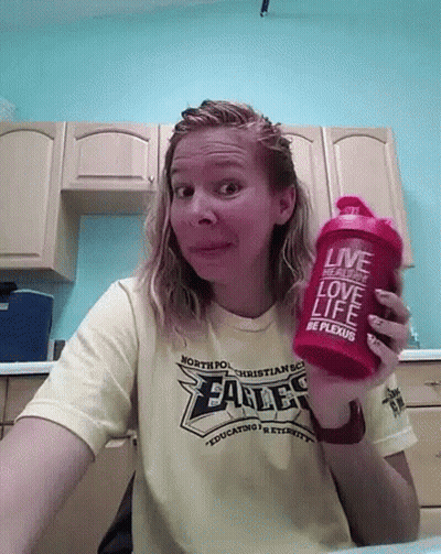 A Woman Wearing A Shirt That Says Eagles Is Holding A Red Shaker GIF