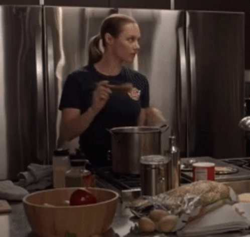 A Woman Wearing A Shirt That Says Firefighter Is Stirring A Pot GIF