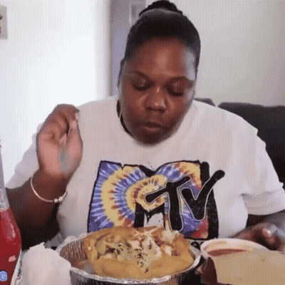 A Woman Wearing A Shirt That Says Mtv Is Eating Food GIF