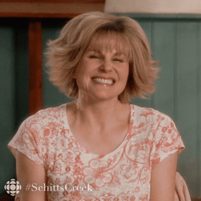 A Woman Wearing A Shirt That Says Schitts Creek Smiles GIF