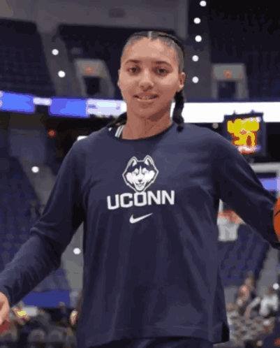 A Woman Wearing A Shirt That Says Uconn Holds A Basketball GIF