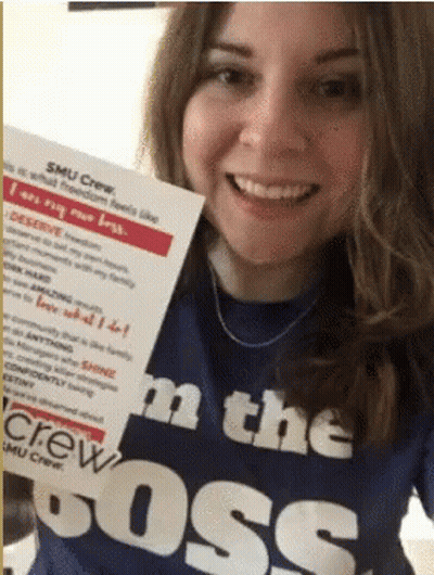 A Woman Wearing A Smu Crew Shirt Is Holding Up A Sign That Says " I Am The Boss " GIF