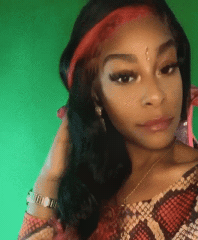 A Woman Wearing A Snake Print Shirt And A Red Headband Is Looking At The Camera . GIF