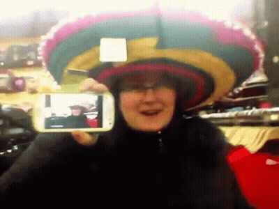A Woman Wearing A Sombrero Is Taking A Picture Of Herself With A Cell Phone GIF