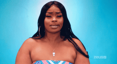 A Woman Wearing A Strapless Top And A Necklace Is Standing In Front Of A Blue Background That Says Zeus On It GIF