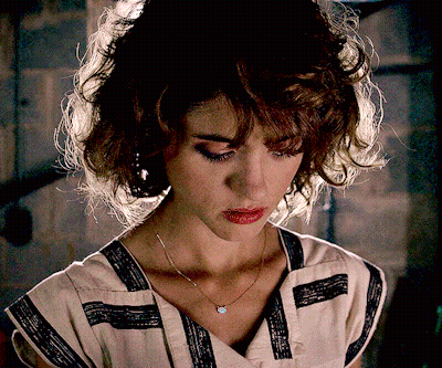 A Woman Wearing A Striped Shirt And A Necklace Looks Down At Something GIF