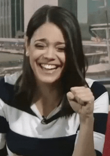 A Woman Wearing A Striped Shirt Is Laughing And Holding Her Hair GIF