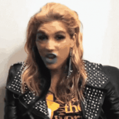 A Woman Wearing A Studded Leather Jacket Is Making A Face GIF