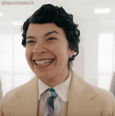 A Woman Wearing A Suit And Tie Is Smiling With The Hashtag Itsscottiesstark GIF
