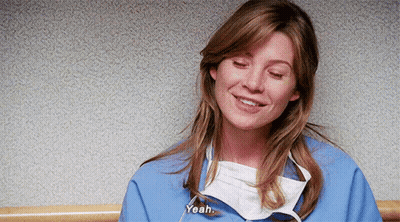 A Woman Wearing A Surgical Mask And A Blue Scrub Is Smiling And Talking . GIF