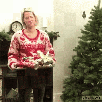 A Woman Wearing A Sweater That Says Merry Christmas Is Holding A Tray Of Christmas Decorations . GIF