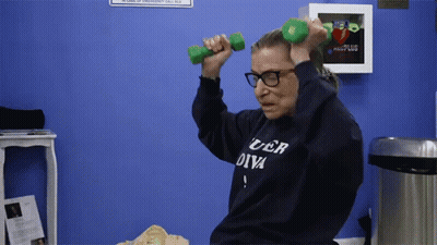 A Woman Wearing A Sweater That Says Uber Diva Is Lifting Dumbbells GIF
