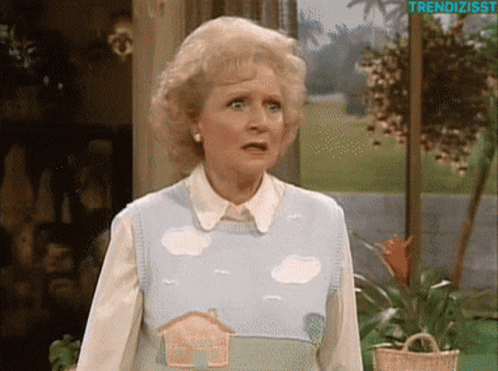 A Woman Wearing A Sweater With A House And Clouds On It GIF