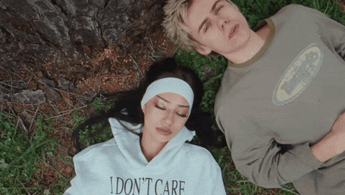 A Woman Wearing A Sweatshirt That Says I Do N't Care Lays Next To A Man GIF