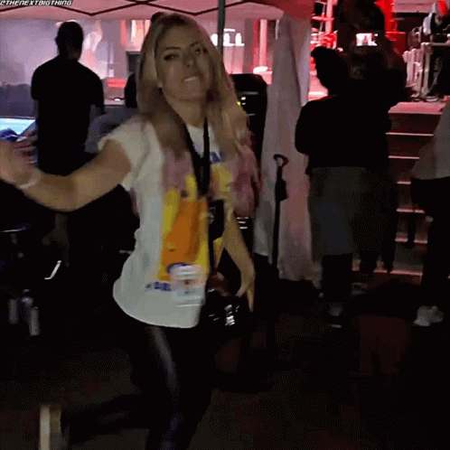 A Woman Wearing A T-Shirt That Says Ambulance Is Dancing In A Crowd GIF