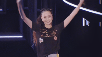 A Woman Wearing A T-Shirt That Says Finally Is Standing On Stage GIF