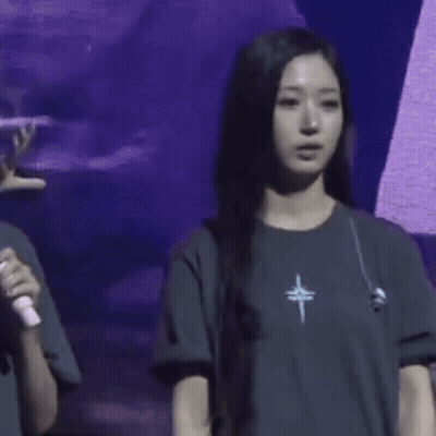 A Woman Wearing A T-Shirt With A Cross On It Is Waving Her Hand GIF