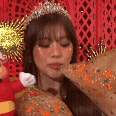 A Woman Wearing A Tiara And A Crown Is Eating A Pizza GIF