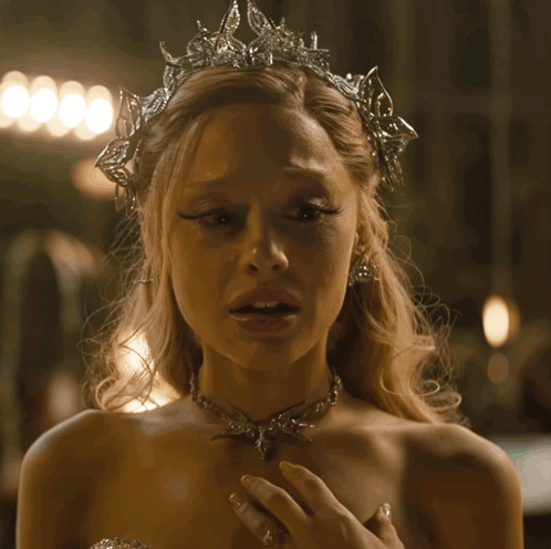 A Woman Wearing A Tiara And A Necklace Has A Sad Look On Her Face GIF