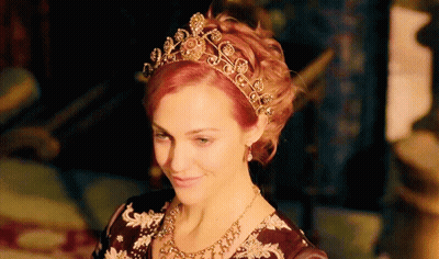 A Woman Wearing A Tiara And Necklace Is Smiling GIF