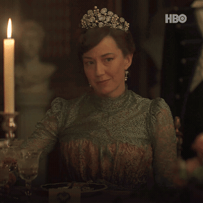 A Woman Wearing A Tiara Is Holding A Glass Of Wine In Front Of A Candle And Hbo Logo GIF