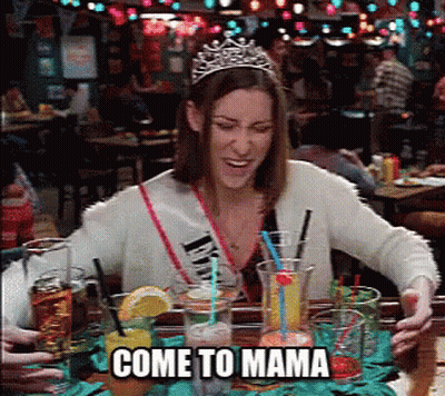 A Woman Wearing A Tiara Is Sitting At A Table With Drinks And The Words Come To Mama Below Her GIF