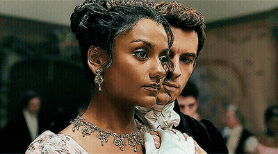 A Woman Wearing A Tiara Is Standing Next To A Man In A Tuxedo GIF