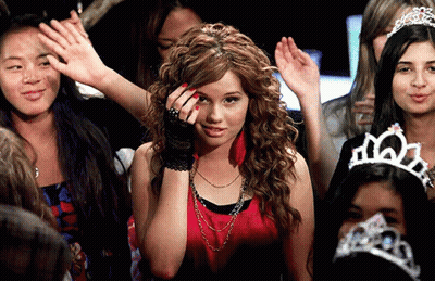 A Woman Wearing A Tiara Stands In A Crowd GIF