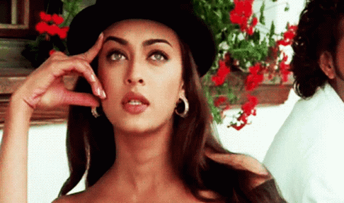 A Woman Wearing A Top Hat And Hoop Earrings Is Thinking GIF