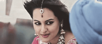 A Woman Wearing A Turban And Earrings Is Looking At A Man . GIF