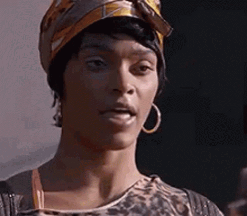 A Woman Wearing A Turban And Hoop Earrings Is Making A Funny Face . GIF