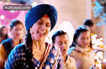 A Woman Wearing A Turban Is Dancing With A Group Of People . GIF