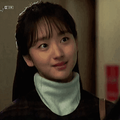 A Woman Wearing A Turtleneck And A Scarf Around Her Neck GIF