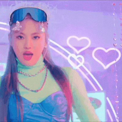 A Woman Wearing A Turtleneck And Goggles Is Standing In Front Of A Purple Wall With Hearts . GIF