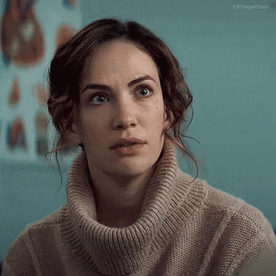 A Woman Wearing A Turtleneck Sweater Is Looking At The Camera . GIF