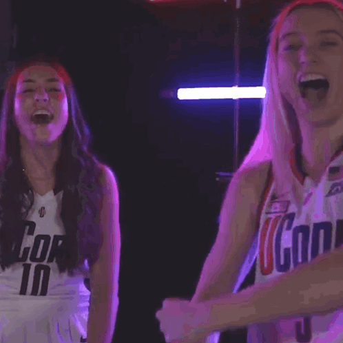 A Woman Wearing A Uconn Jersey Flexes Her Muscles GIF