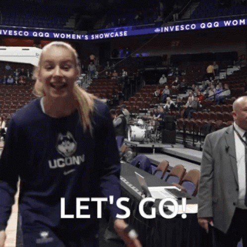 A Woman Wearing A Uconn Shirt Says Let 'S Go In Front Of A Crowd GIF