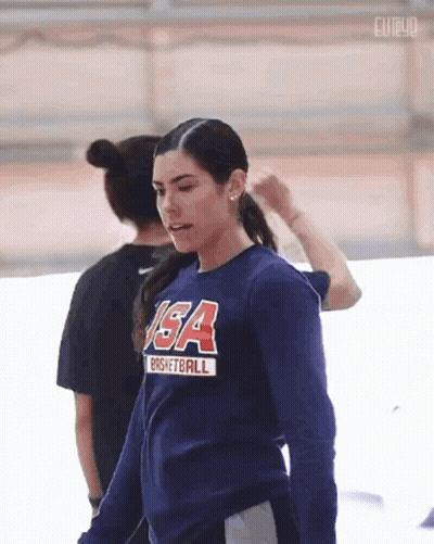 A Woman Wearing A Usa Basketball Shirt Is Standing In A Gym . GIF